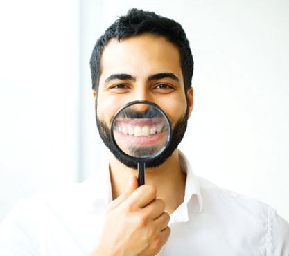 man holding magnifying glass to his smile